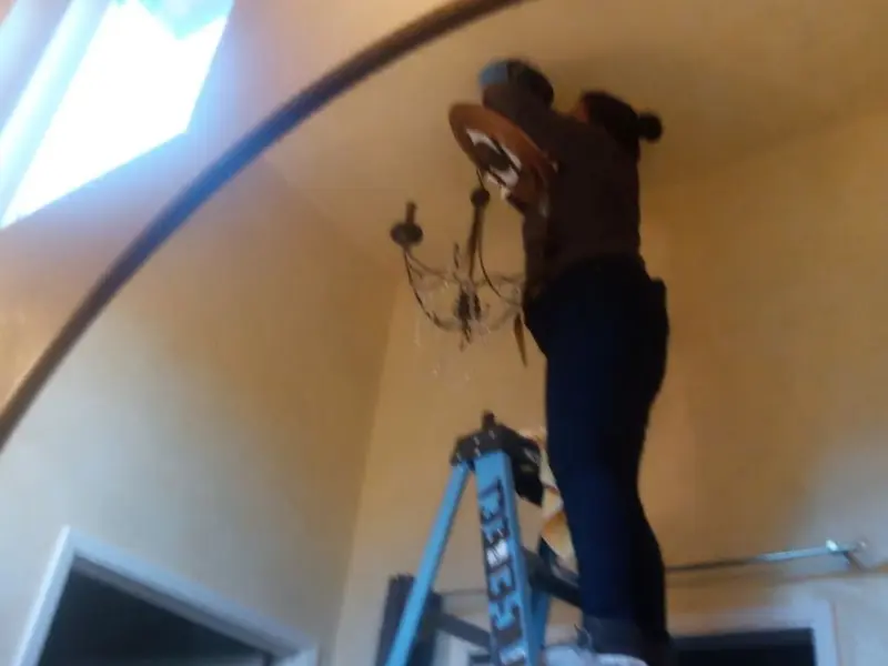 Electrician installing a chandelier in a Gantt residence